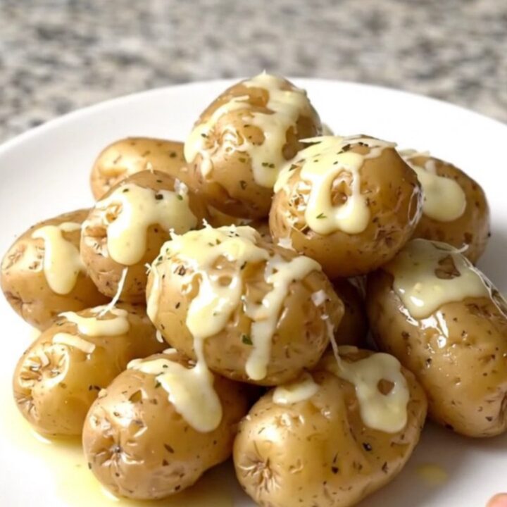 A top-down view of raw halved baby potatoes in a black slow cooker, ready to be seasoned.