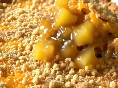 A top-down view of a vintage pineapple cheddar casserole in a white dish with a golden, crispy cracker crust.