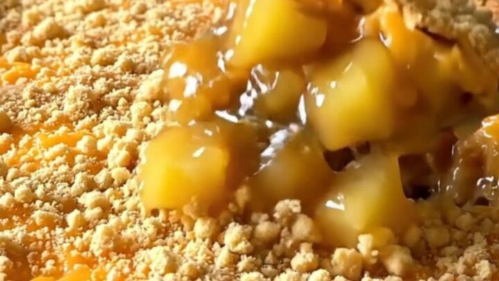 A top-down view of a vintage pineapple cheddar casserole in a white dish with a golden, crispy cracker crust.