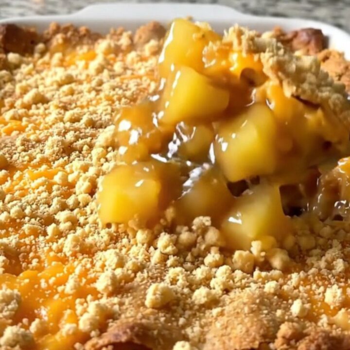 A top-down view of a vintage pineapple cheddar casserole in a white dish with a golden, crispy cracker crust.