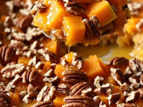 A ceramic baking dish filled with golden-brown roasted butternut squash cubes glazed in maple butter and topped with toasted