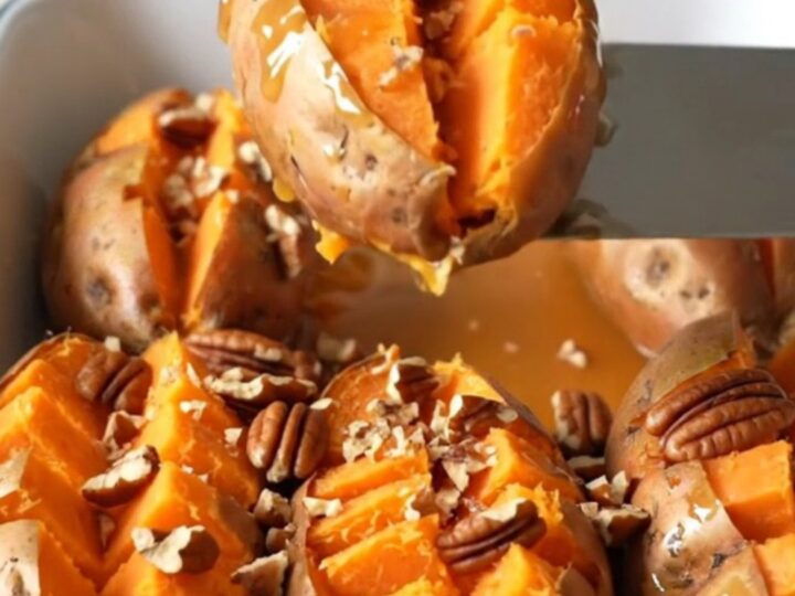 A close-up of baked hasselback sweet potatoes in a white baker