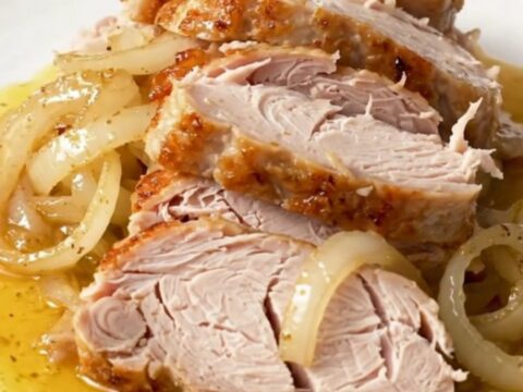 A close-up view of the slow-cooked Cajun butter turkey breast resting in a black slow cooker insert.