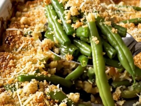 A top-down view of a rectangular white ceramic dish filled with vibrant green beans topped with golden parmesan breadcrumbs.