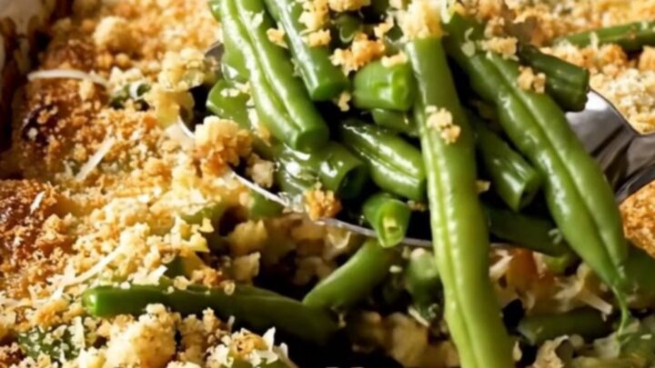 A top-down view of a rectangular white ceramic dish filled with vibrant green beans topped with golden parmesan breadcrumbs.