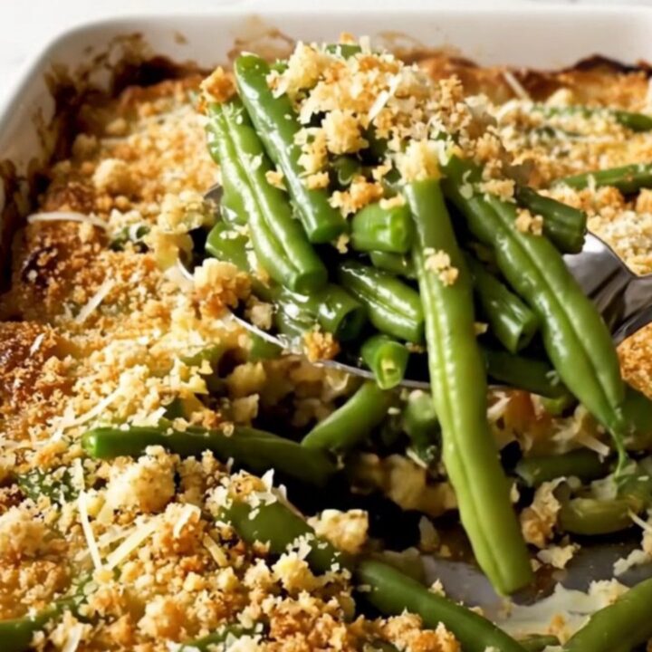 A top-down view of a rectangular white ceramic dish filled with vibrant green beans topped with golden parmesan breadcrumbs.