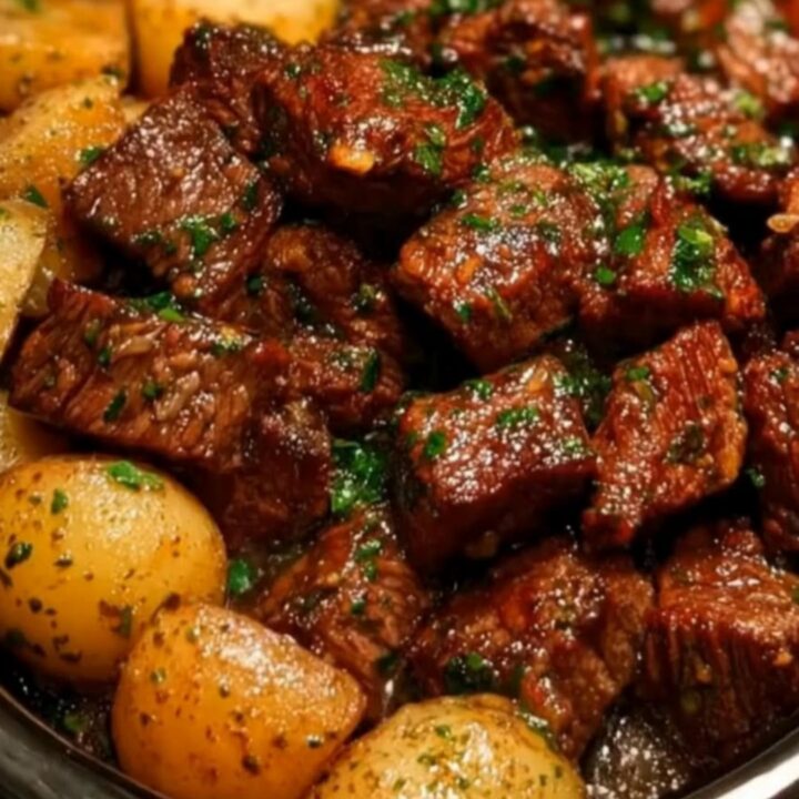 Slow cooker garlic butter beef bites and halved baby potatoes garnished with fresh chopped parsley