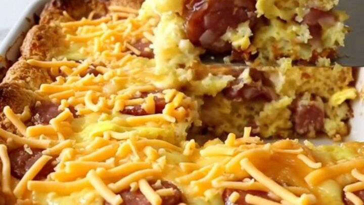 A golden, puffed smoked sausage cornbread casserole in a white ceramic dish.