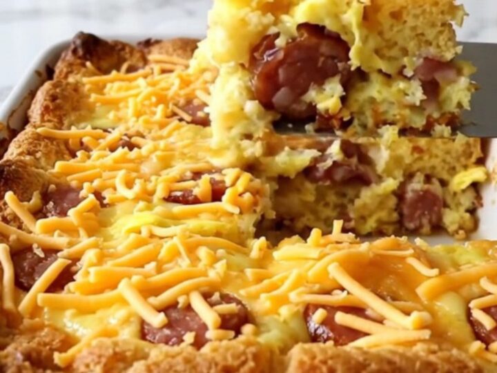 A golden, puffed smoked sausage cornbread casserole in a white ceramic dish.