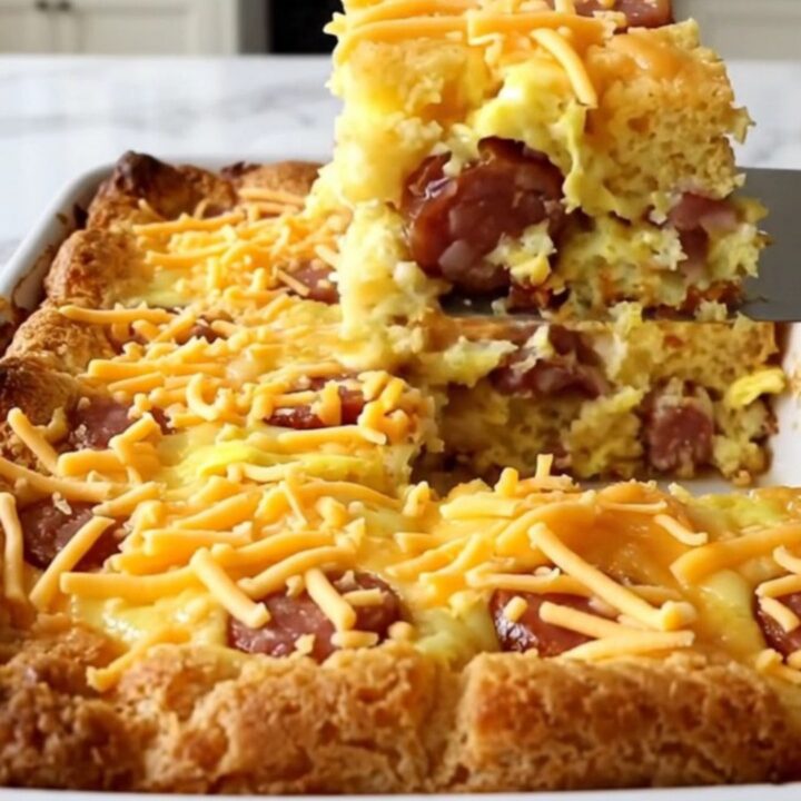 A golden, puffed smoked sausage cornbread casserole in a white ceramic dish.
