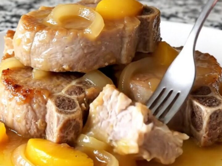 Juicy slow-cooked pork loin slices topped with caramelized peaches and onions in a savory sauce.