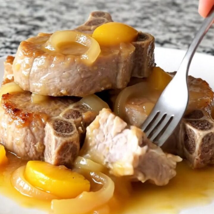 Juicy slow-cooked pork loin slices topped with caramelized peaches and onions in a savory sauce.