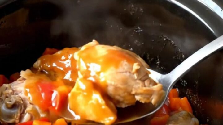 A close-up of volcano chicken bites in a slow cooker, featuring glossy sauce and red peppers.