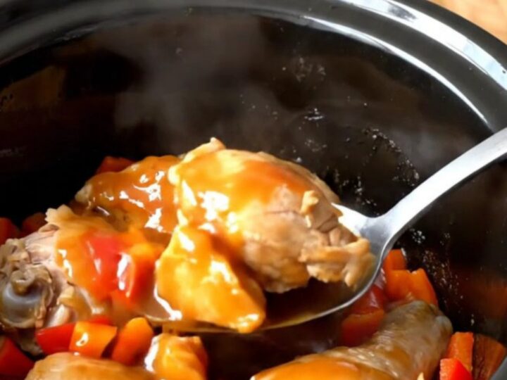 A close-up of volcano chicken bites in a slow cooker, featuring glossy sauce and red peppers.