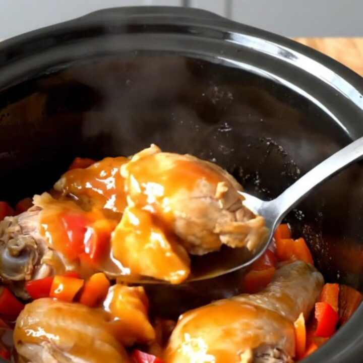 A close-up of volcano chicken bites in a slow cooker, featuring glossy sauce and red peppers.