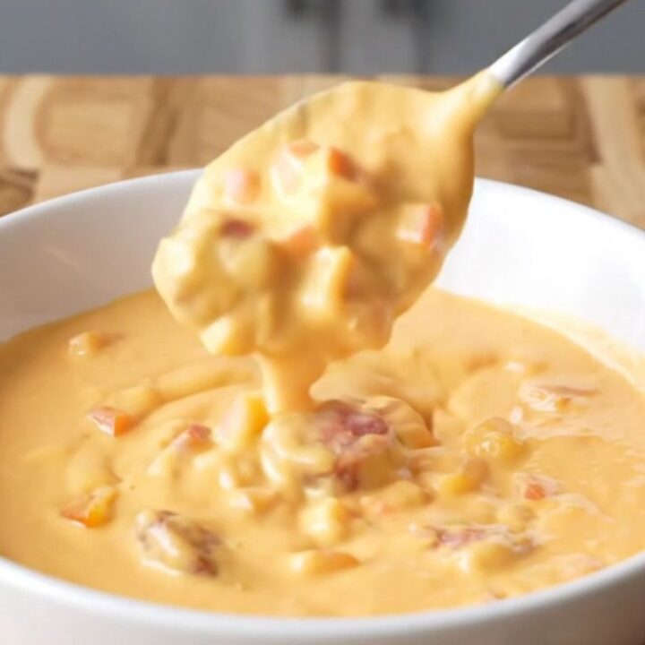 A close-up view of creamy, pale orange Cajun queso in a slow cooker