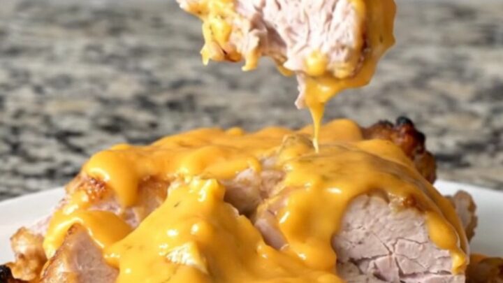 A slow cooker filled with pork tenderloin, baby potatoes, and melted cheddar cheese sauce.
