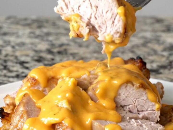 A slow cooker filled with pork tenderloin, baby potatoes, and melted cheddar cheese sauce.