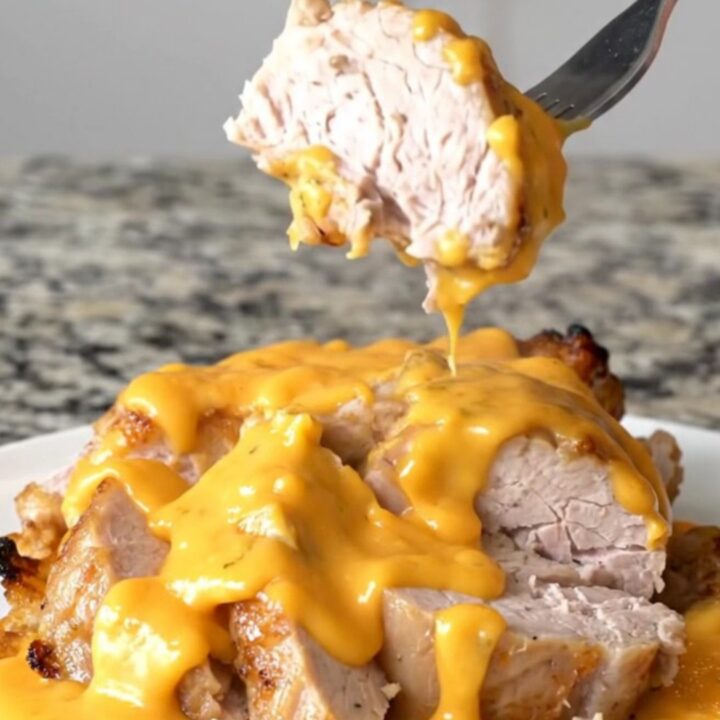 A slow cooker filled with pork tenderloin, baby potatoes, and melted cheddar cheese sauce.