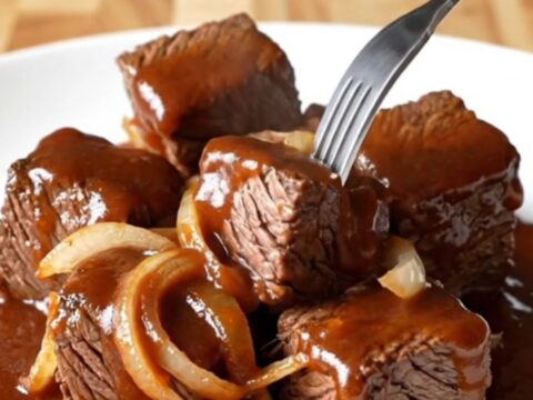 A close-up of tender, caramelized beef chuck roast burnt ends coated in a rich, dark barbecue sauce.