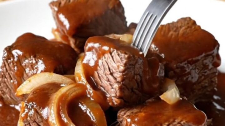 A close-up of tender, caramelized beef chuck roast burnt ends coated in a rich, dark barbecue sauce.