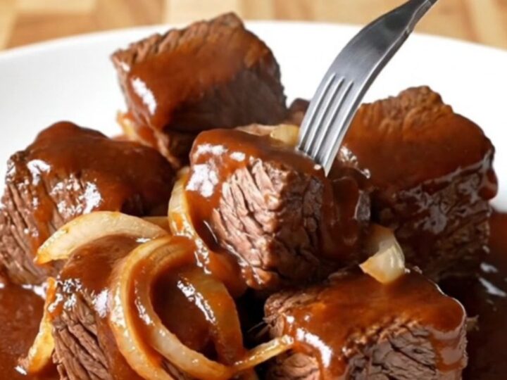 A close-up of tender, caramelized beef chuck roast burnt ends coated in a rich, dark barbecue sauce.