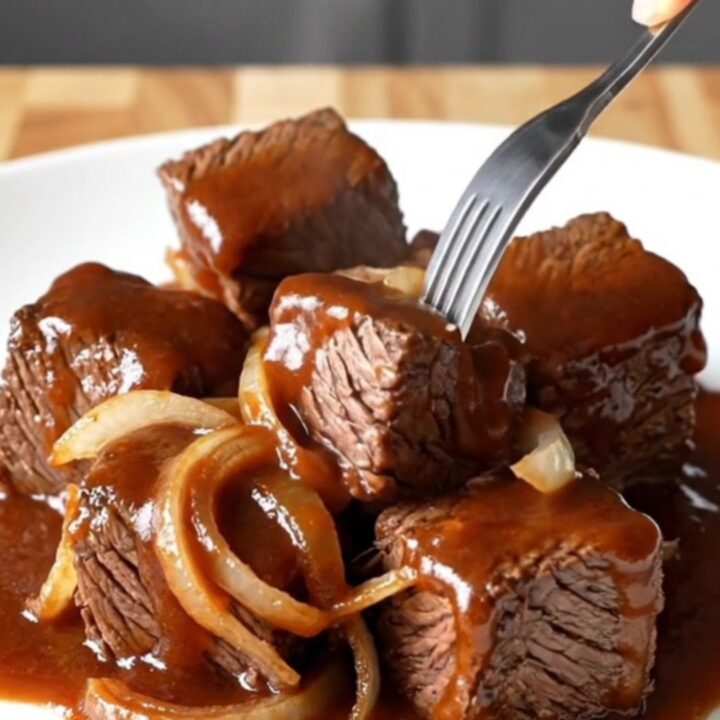 A close-up of tender, caramelized beef chuck roast burnt ends coated in a rich, dark barbecue sauce.