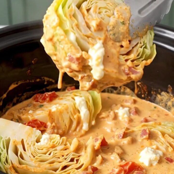 Slow cooker filled with tender green cabbage wedges, bacon, and a rich creamy orange sauce.