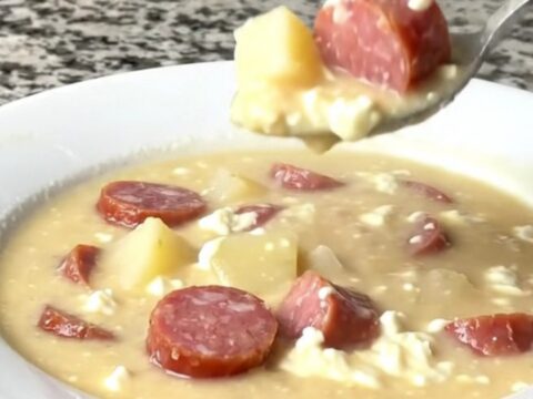 A close-up view of the creamy kielbasa potato soup in a black slow cooker insert, showing chunks of potato and sausage.