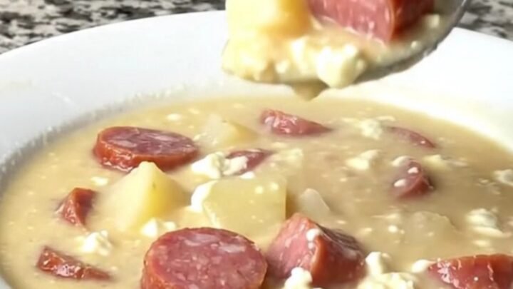 A close-up view of the creamy kielbasa potato soup in a black slow cooker insert, showing chunks of potato and sausage.