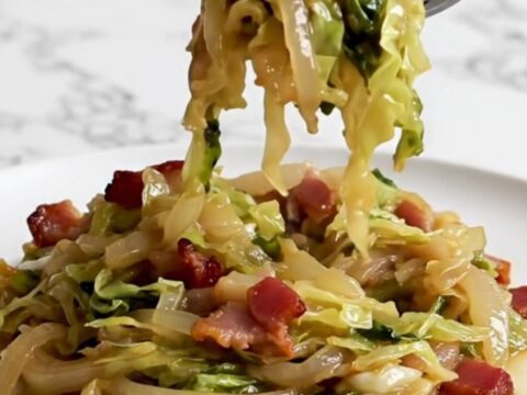 A close-up of tender, slow-cooked German hot bacon cabbage served on a white plate.