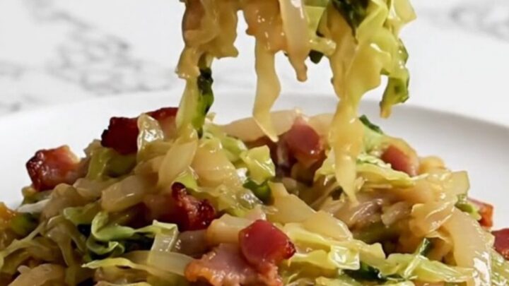 A close-up of tender, slow-cooked German hot bacon cabbage served on a white plate.