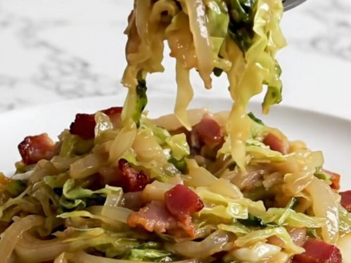 A close-up of tender, slow-cooked German hot bacon cabbage served on a white plate.