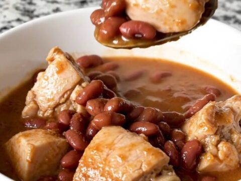 A slow cooker filled with chicken, red beans, and andouille sausage in a rich, seasoned broth.