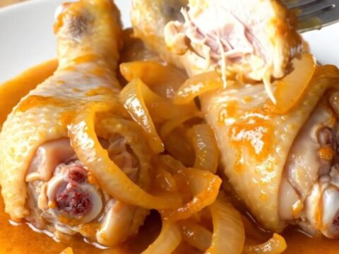 A close-up view of orange soda glazed chicken drumsticks on a white plate, showing a thick, shiny