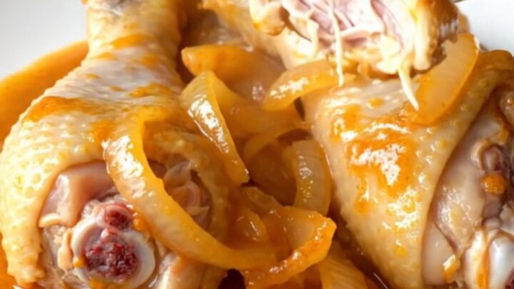 A close-up view of orange soda glazed chicken drumsticks on a white plate, showing a thick, shiny