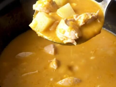 A close-up view of the finished creamy beer cheese chicken and potato soup in a black slow cooker insert.