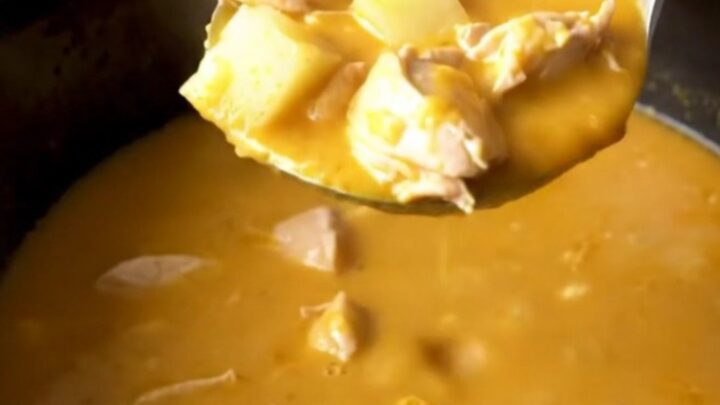 A close-up view of the finished creamy beer cheese chicken and potato soup in a black slow cooker insert.