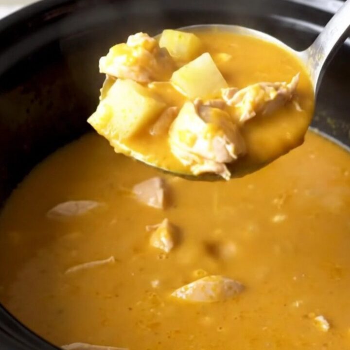 A close-up view of the finished creamy beer cheese chicken and potato soup in a black slow cooker insert.