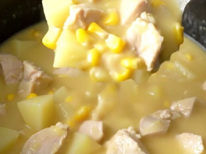 A creamy, white chowder in a slow cooker filled with chicken chunks, corn, and potatoes.