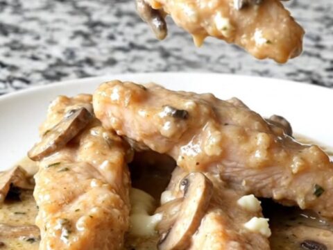 A plate of creamy slow cooker Angel Chicken tenders with sautéed mushrooms and a rich herb sauce.