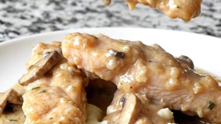 A plate of creamy slow cooker Angel Chicken tenders with sautéed mushrooms and a rich herb sauce.