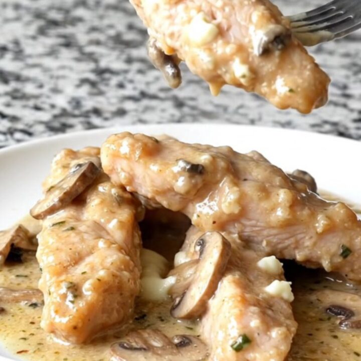A plate of creamy slow cooker Angel Chicken tenders with sautéed mushrooms and a rich herb sauce.