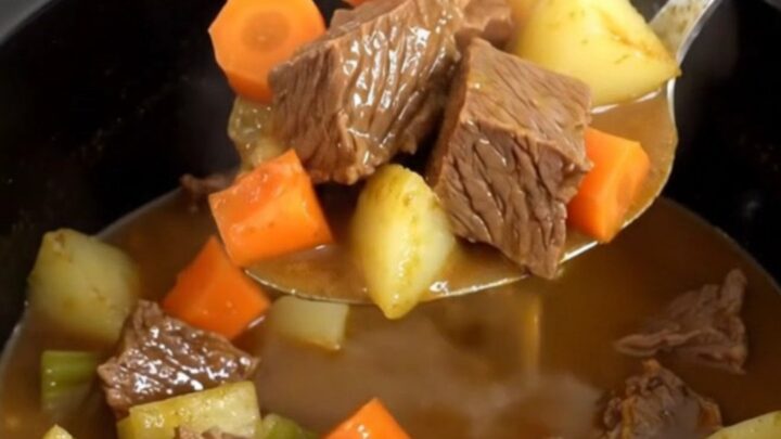 A close-up of beef pot roast potato soup in a black slow cooker insert, showing tender beef and vegetables.
