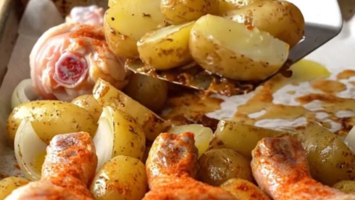 Crispy golden-brown chicken drumsticks roasted on a sheet pan with baby potatoes and onions.