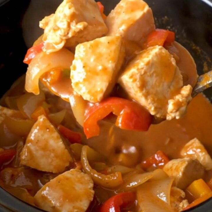 A close-up view of Crockpot Tex-Mex Chicken Guisada in a black slow cooker insert