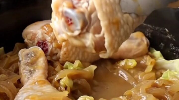 Slow cooker filled with chicken drumsticks and cabbage wedges in a savory onion sauce.