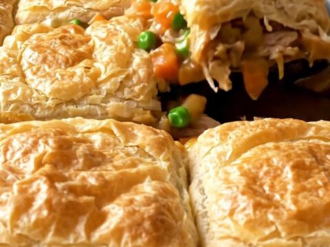 A golden, crispy sheet pan turkey pot pie with visible chunks of turkey and vegetables.