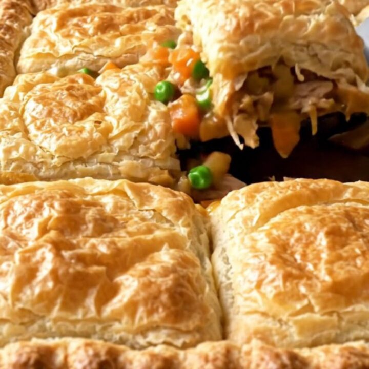 A golden, crispy sheet pan turkey pot pie with visible chunks of turkey and vegetables.