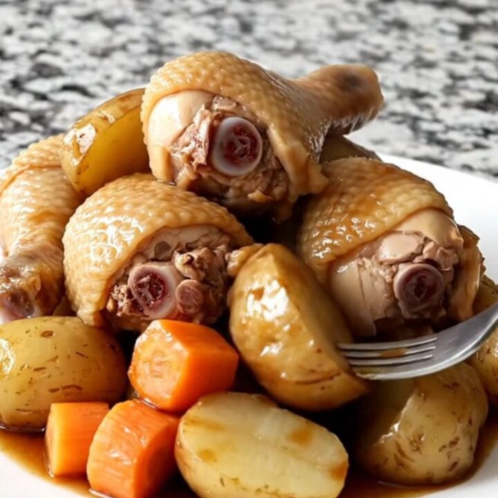 A close-up of slow cooker Korean-style soy-braised chicken drumsticks with soft potatoes and carrots.
